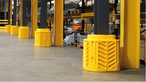 Column protectors installed on pallet rack uprights in a warehouse — impact-absorbing polymer guards in OSHA-compliant high-visibility colors